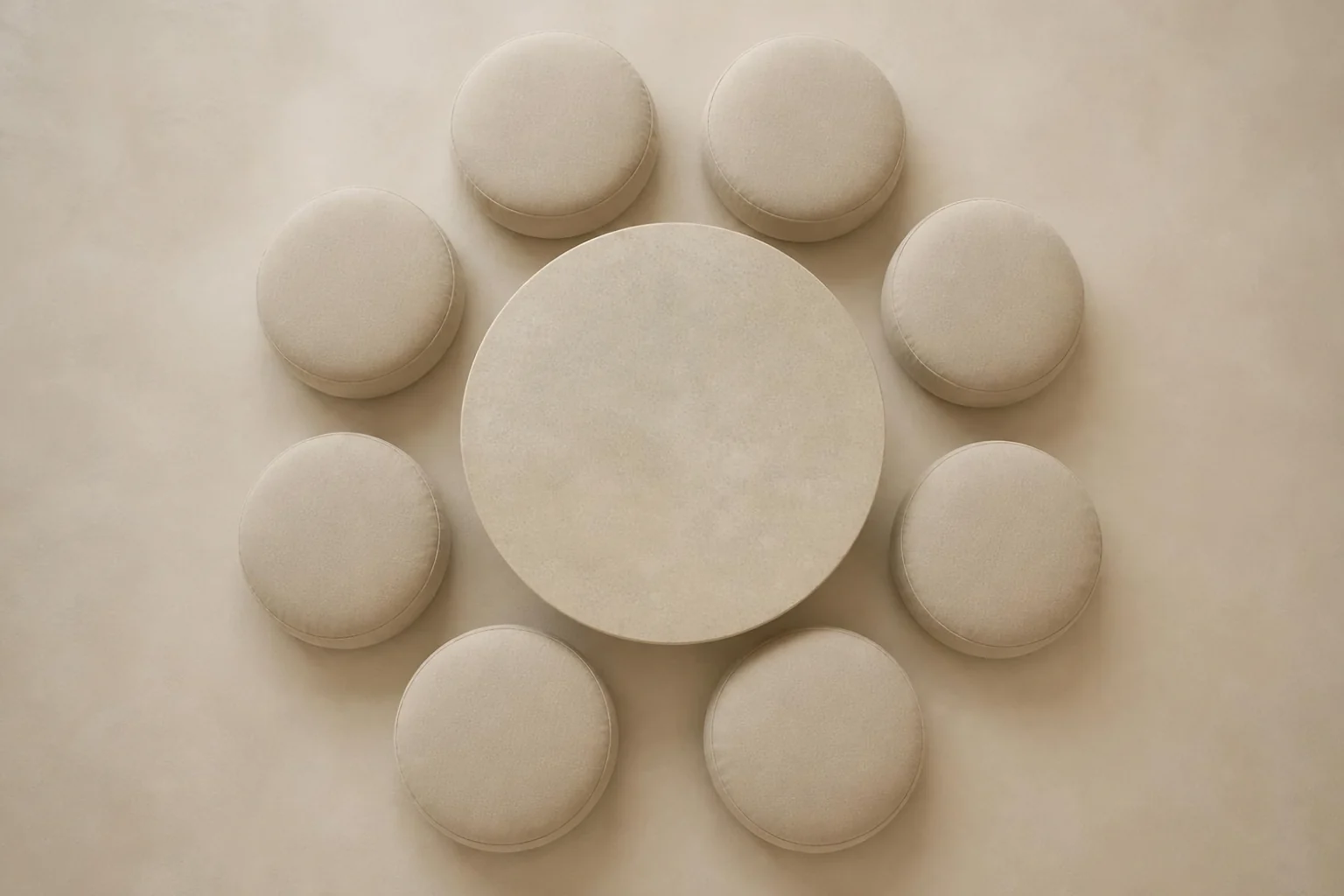 A circle of linen floor cushions around a round stone table